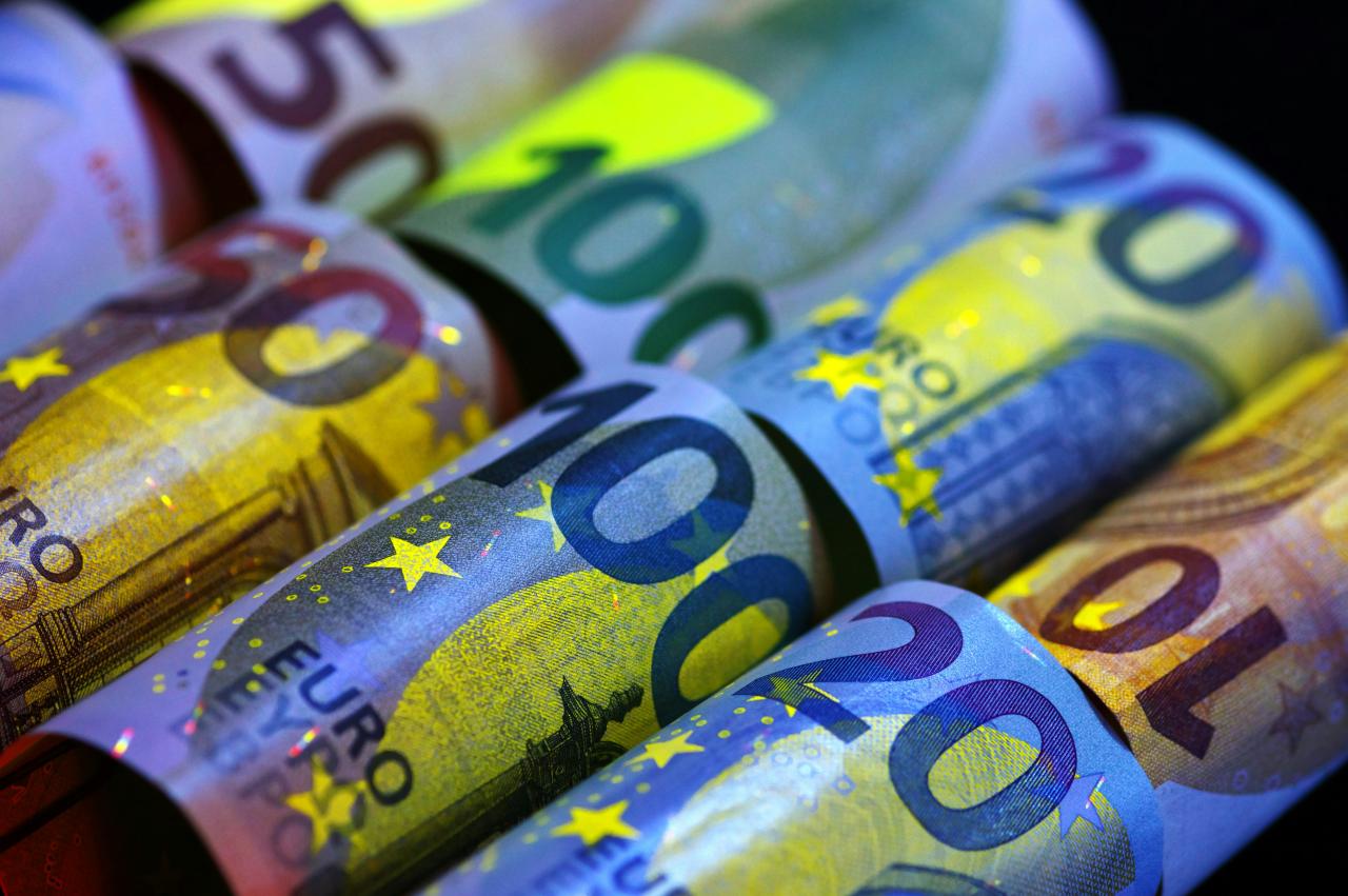 Uang kertas euro yang digulung menyala di bawah sinar uv.